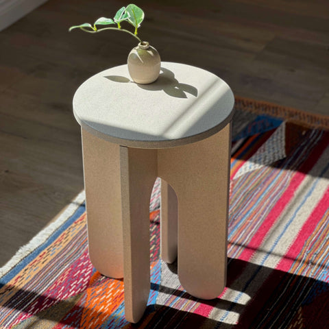 Light Stone stool featuring a minimalist design with organic texture and a small plant, perfect for home decor.