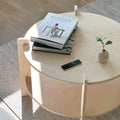 Stylish round coffee table with books, a remote, and a small plant accenting a modern living room.