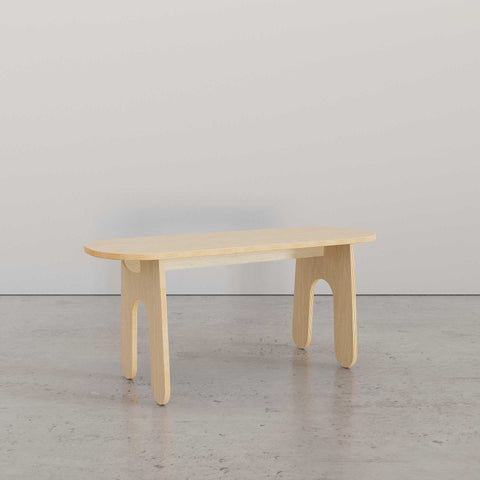 Minimalist wooden coffee table with rounded edges and unique leg design, set against a neutral background.
