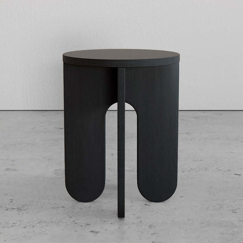 Modern black side table with a minimalist design, featuring a round top and unique arch-shaped legs.