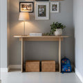 Modern Console Table in stylish entryway with lamp, photos, and decorative plants.