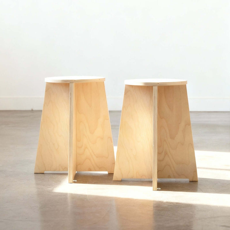 Two wooden stools with a minimalist design on a reflective floor.