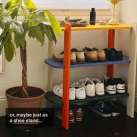 Colorful shoe rack displaying various shoes with a potted plant nearby in a cozy interior setting.