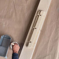 A person painting an unfinished wall shelf on a brown surface, showcasing DIY customization options.