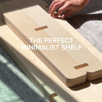 Hand assembling a modern minimalist shelf design, showcasing its sleek wood structure and clean lines.