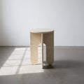 Unfinished modern side table with geometric base in warehouse setting