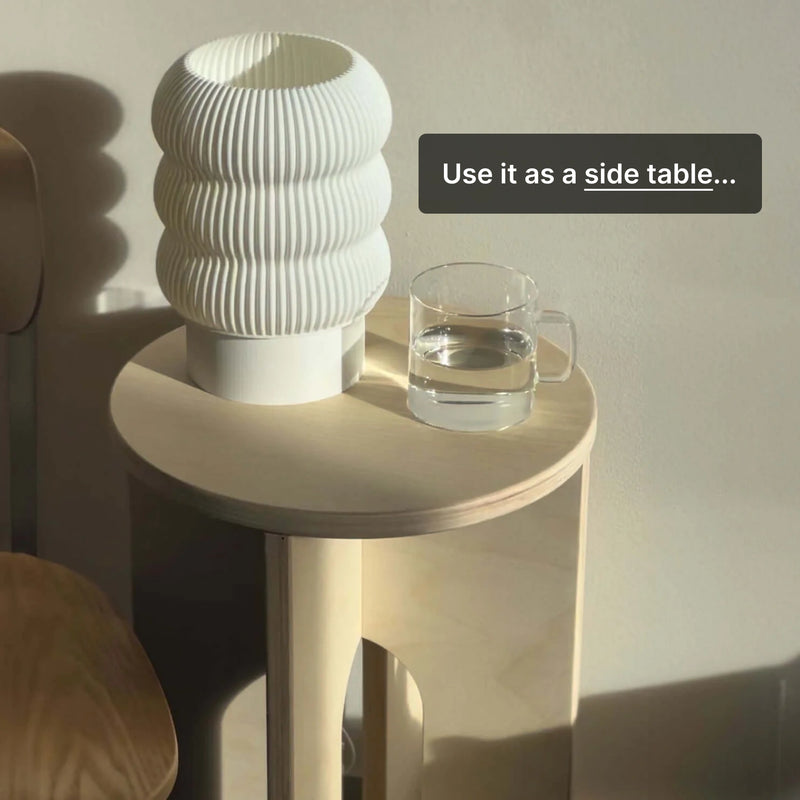 Modern side table featuring a white lamp and a glass of water, showcasing versatile home decor.